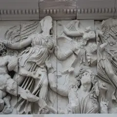 Antyczne rzeźby, jak ten fragment fryzu z Pergamonu, ukazują dynamiczne sceny walki. Widać tu skrzydlate postacie i walczących ludzi, co stanowi wspaniałe przykłady rzeźby antycznej.