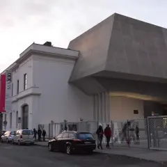 Rzymskie MAXXI, muzeum sztuki nowoczesnej, z charakterystyczną betonową bryłą i wiszącymi banerami wystaw.