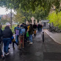Kolejka do kasy biletowej przy Muzeum Historii Naturalnej w Berlinie. W tle budynek muzeum i drzewa.