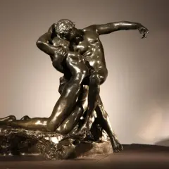 Brązowa rzeźba przedstawiająca parę w namiętnym uścisku, symbolizująca wieczną miłość i pożądanie.