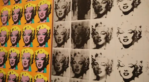Wielokrotne portrety Marilyn Monroe w stylu serigrafia pop art, w jaskrawych kolorach i czarno-białych wersjach, tworzą ikoniczną kompozycję.
