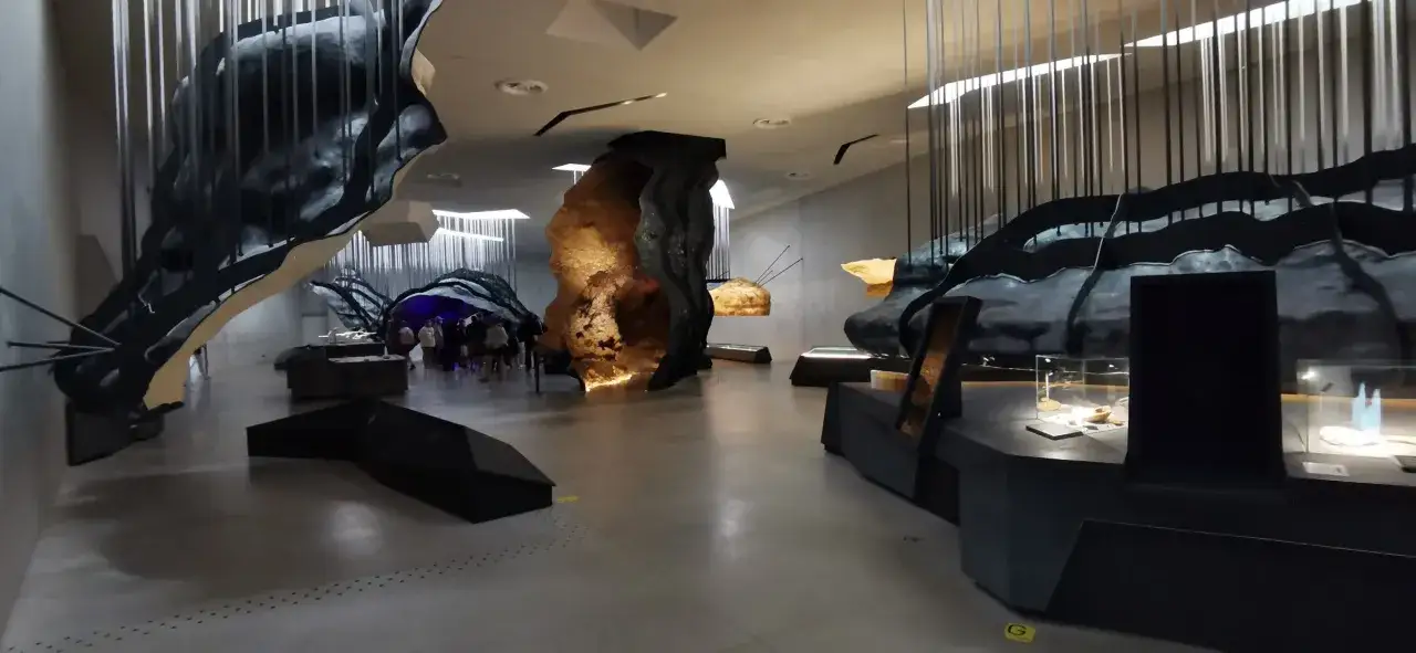 Wystawa prezentuje rekonstrukcję jaskini z malowidłami z Lascaux, z grupą zwiedzających podziwiającą prehistoryczne dzieła sztuki.