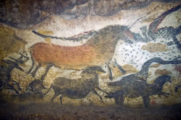 Przykłady malarstwa prehistorycznego: malowidła naskalne przedstawiające zwierzęta, takie jak konie i bizony, namalowane naturalnymi barwnikami na ścianie jaskini.
