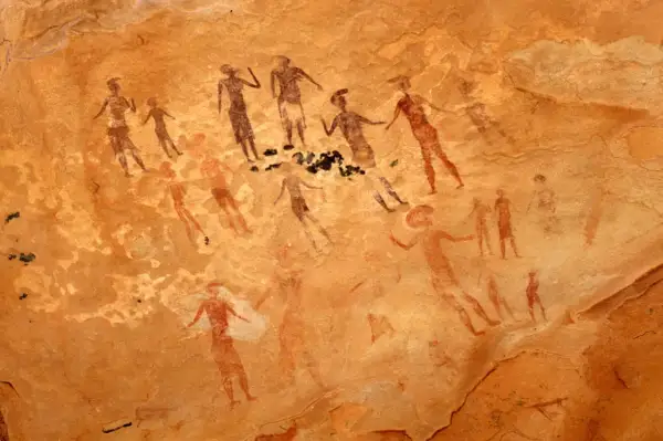 Prehistoryczne malarstwo jaskiniowe ukazuje grupę postaci ludzkich w ruchu, być może podczas rytuału lub polowania.